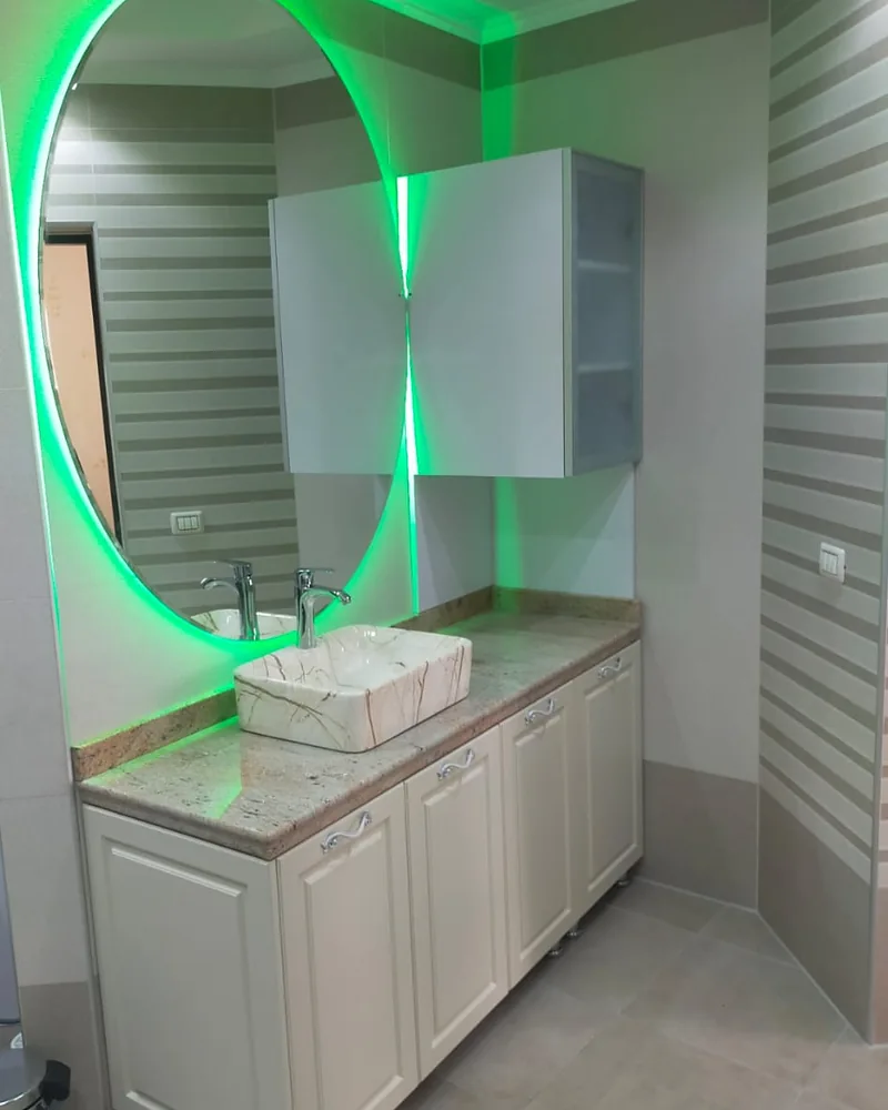 Bespoke bathroom vanity with wall cabinets and an illuminated round mirror