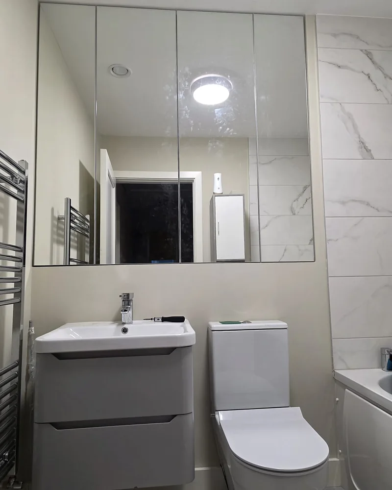 Wall-to-wall mirrored bathroom cabinetry above a fitted vanity unit