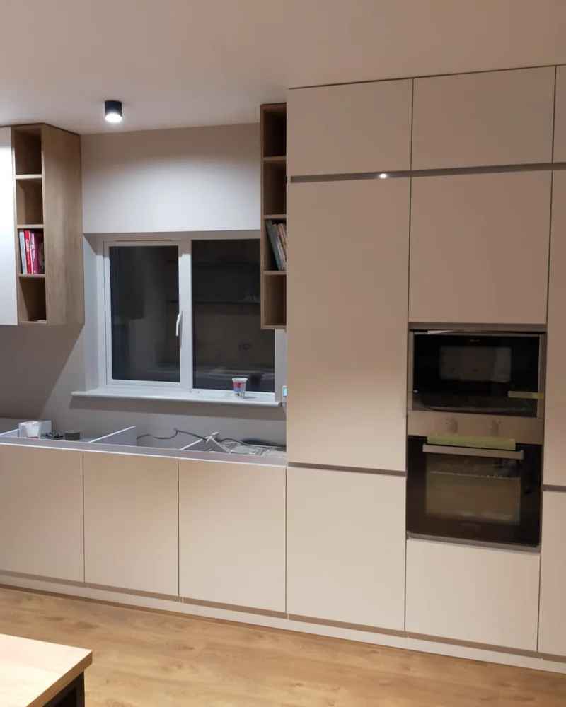 A modern neutral handleless kitchen with tall appliance cabinets, a compact sink run and clean lines.