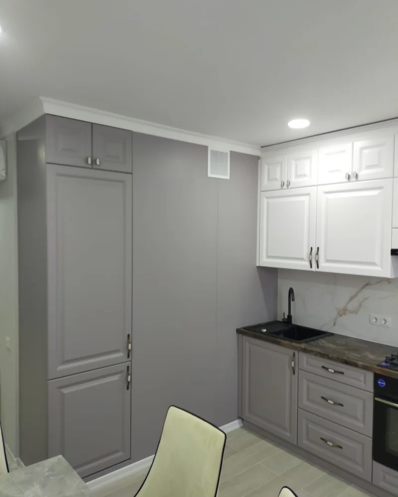 A view of tall grey shaker storage and white wall cabinets in a traditional fitted kitchen.