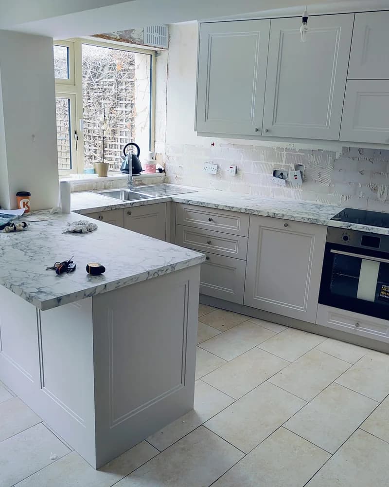 An alternative view of a white shaker kitchen with a central island and bright worktops.