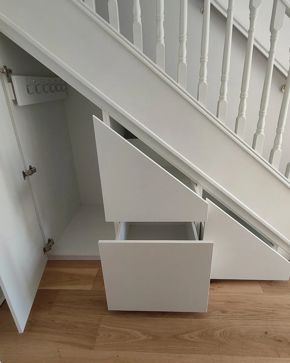 Open bespoke under-stairs storage showing fitted drawers and shelving