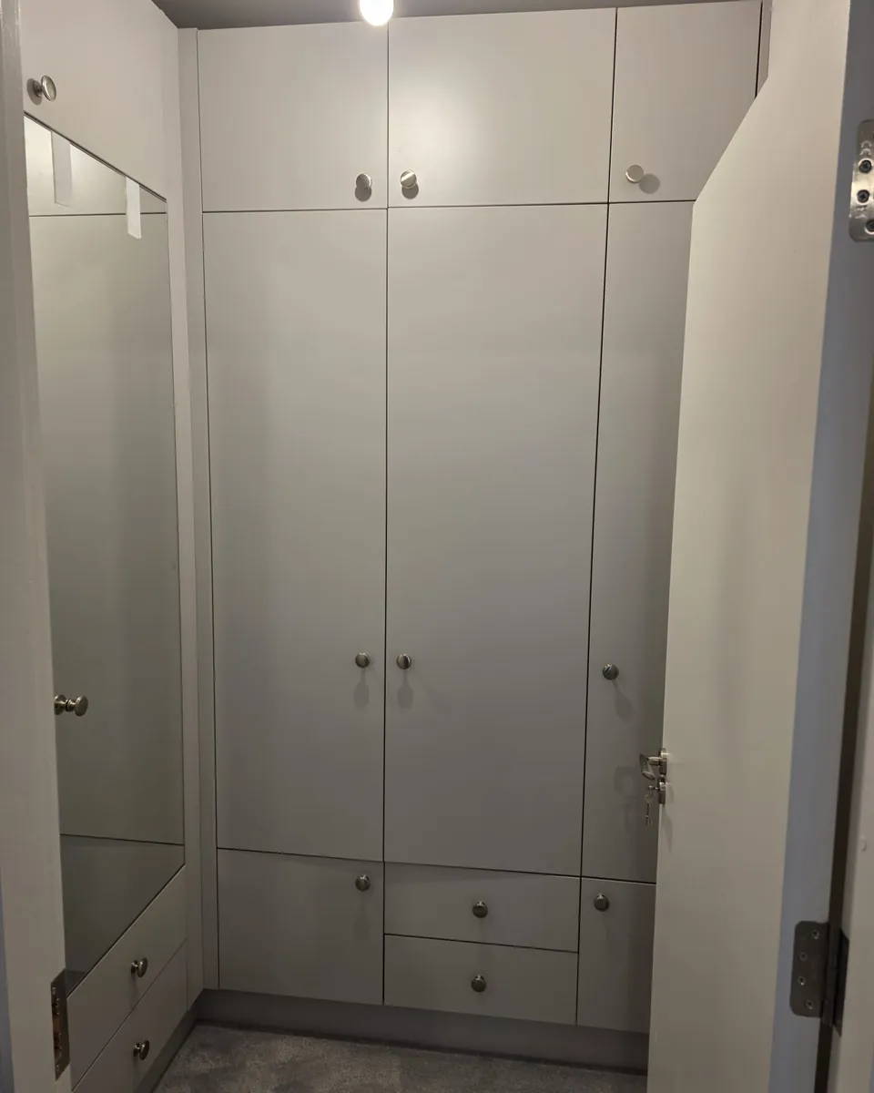 Floor-to-ceiling hallway storage with drawers and mirrored side panels