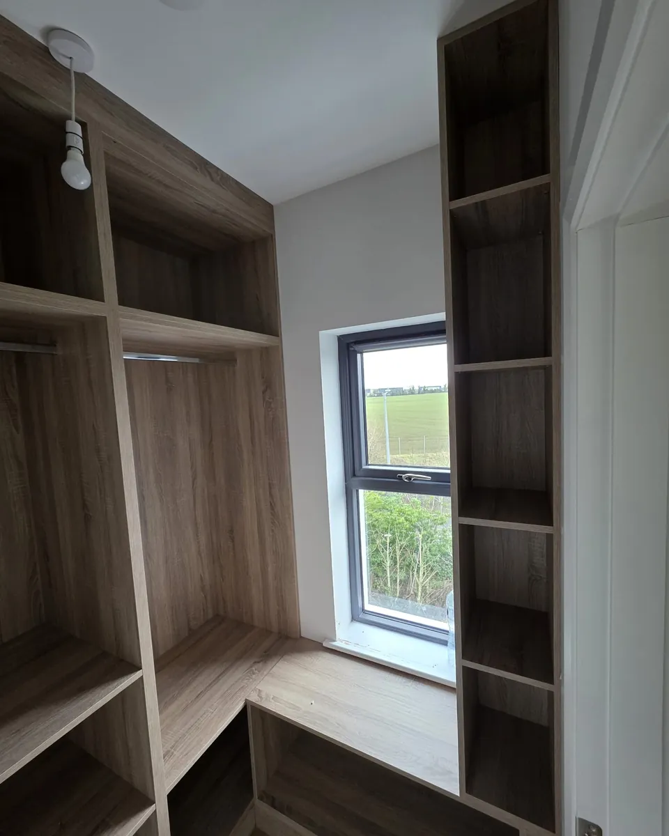 Custom timber-effect storage built around a window with shelves and a bench