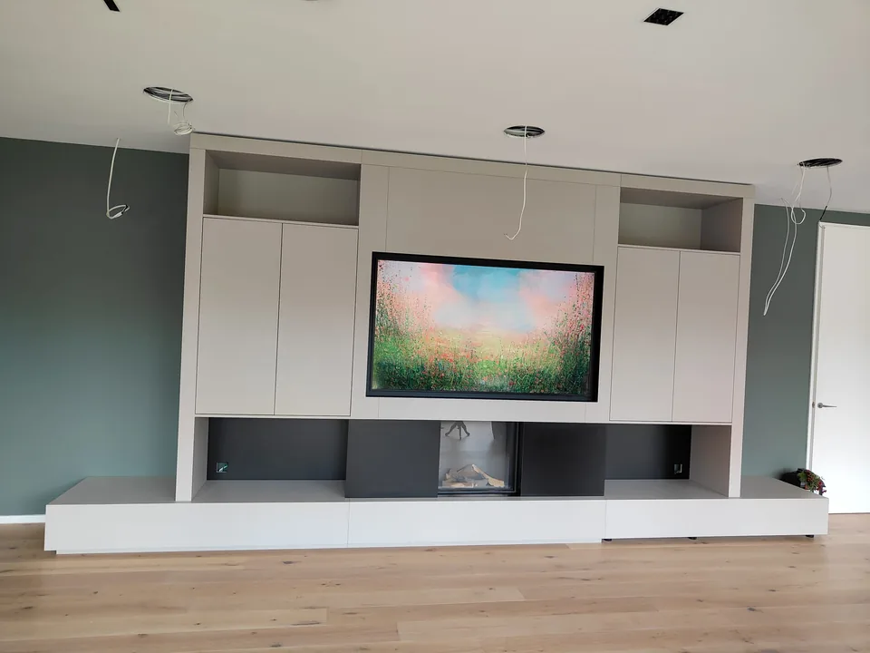 Finished built-in TV media wall with white cabinetry, display shelves and fireplace
