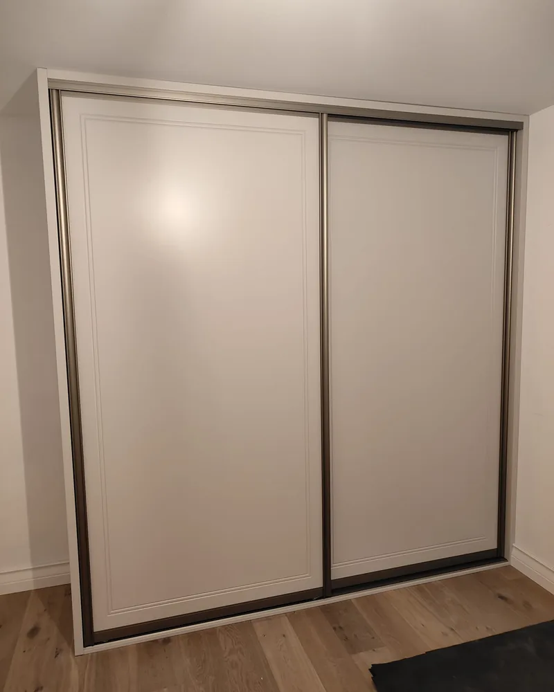 A neutral two-door sliding wardrobe fitted neatly between the bedroom walls.