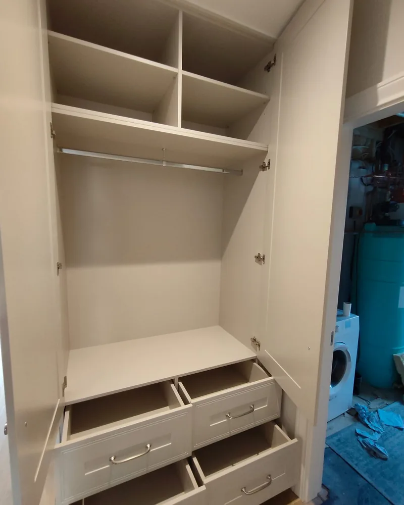 An open wardrobe interior with hanging space, shelves, drawers and practical pull-out wire baskets.