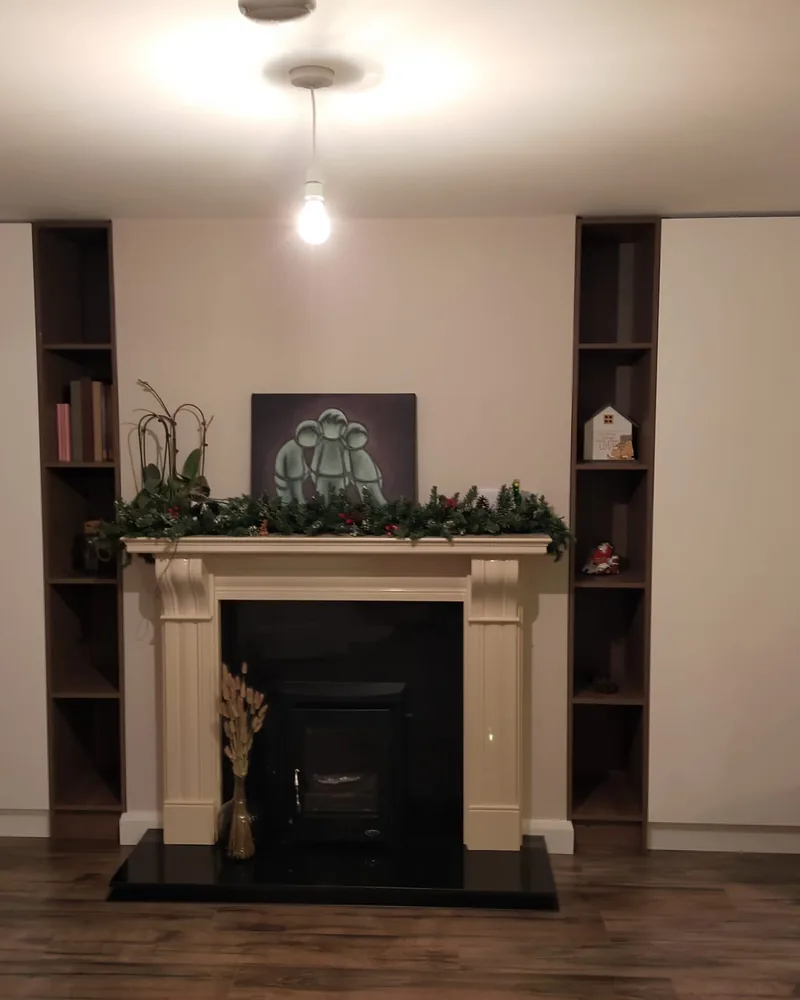 A symmetrical fitted storage wall around a fireplace with tall cupboards and dark open display shelving.