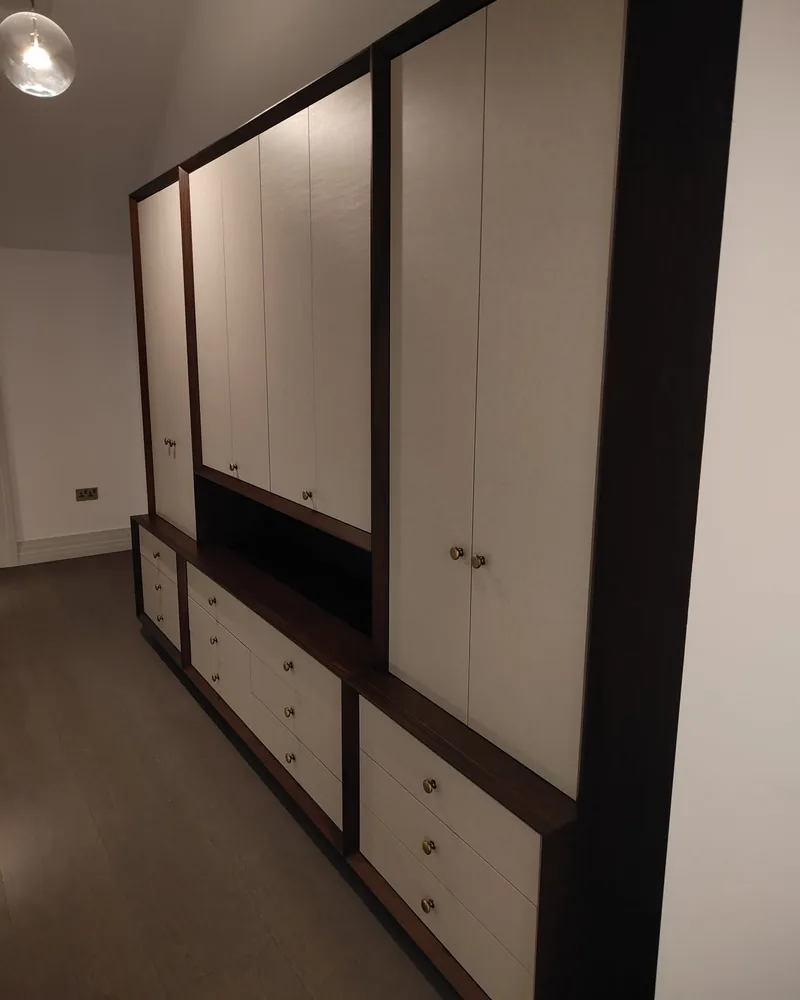 A black and white fitted wardrobe wall with mirrored doors, drawers and contrasting framing.
