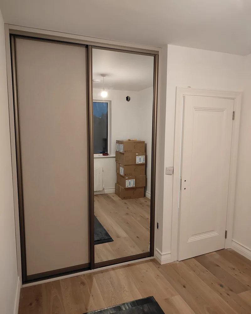 A fitted mirrored sliding wardrobe with dark framing and a clean closed-door appearance.